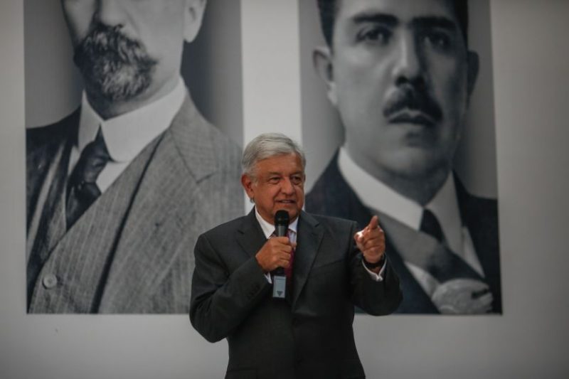 AMLO standing in front of portraits of Madero and Lázaro Cárdenas